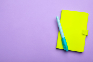 Photo of Green notebook and marker on lilac background, top view. Space for text