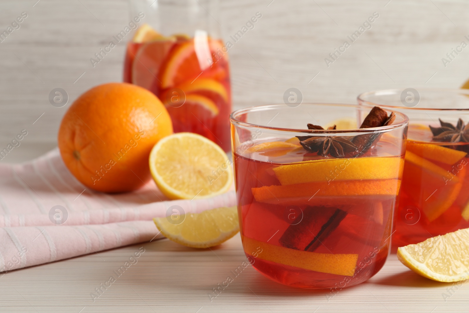 Photo of Aromatic punch drink and ingredients on white wooden table. Space for text