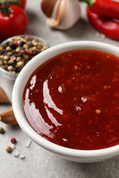 Photo of Spicy chili sauce in bowl on grey table, closeup