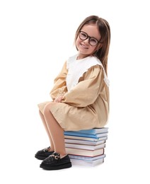 Cute little girl in glasses sitting on stack of books against white background