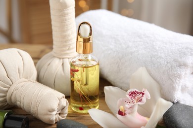 Photo of Beautiful spa composition with essential oil and orchid flower on wooden table against blurred lights, closeup
