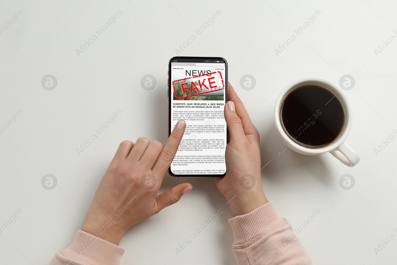 Image of Fake information. Woman using mobile phone to read news at white table, closeup