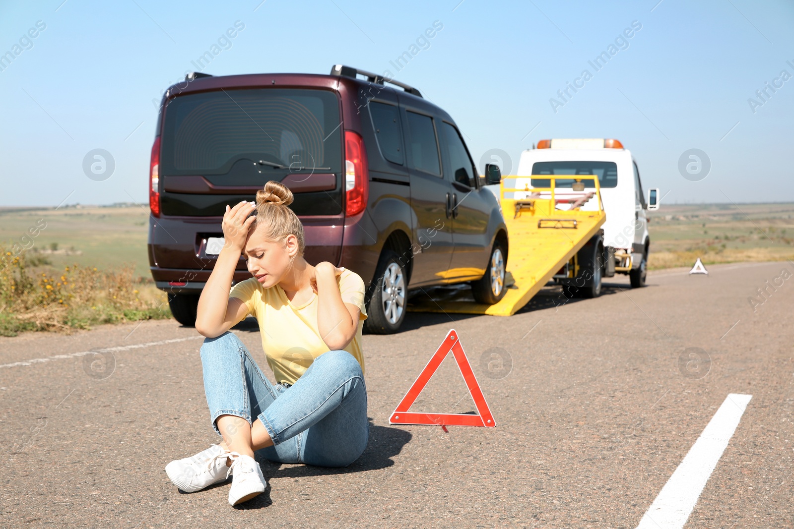 Photo of Woman near broken car and tow truck on country road