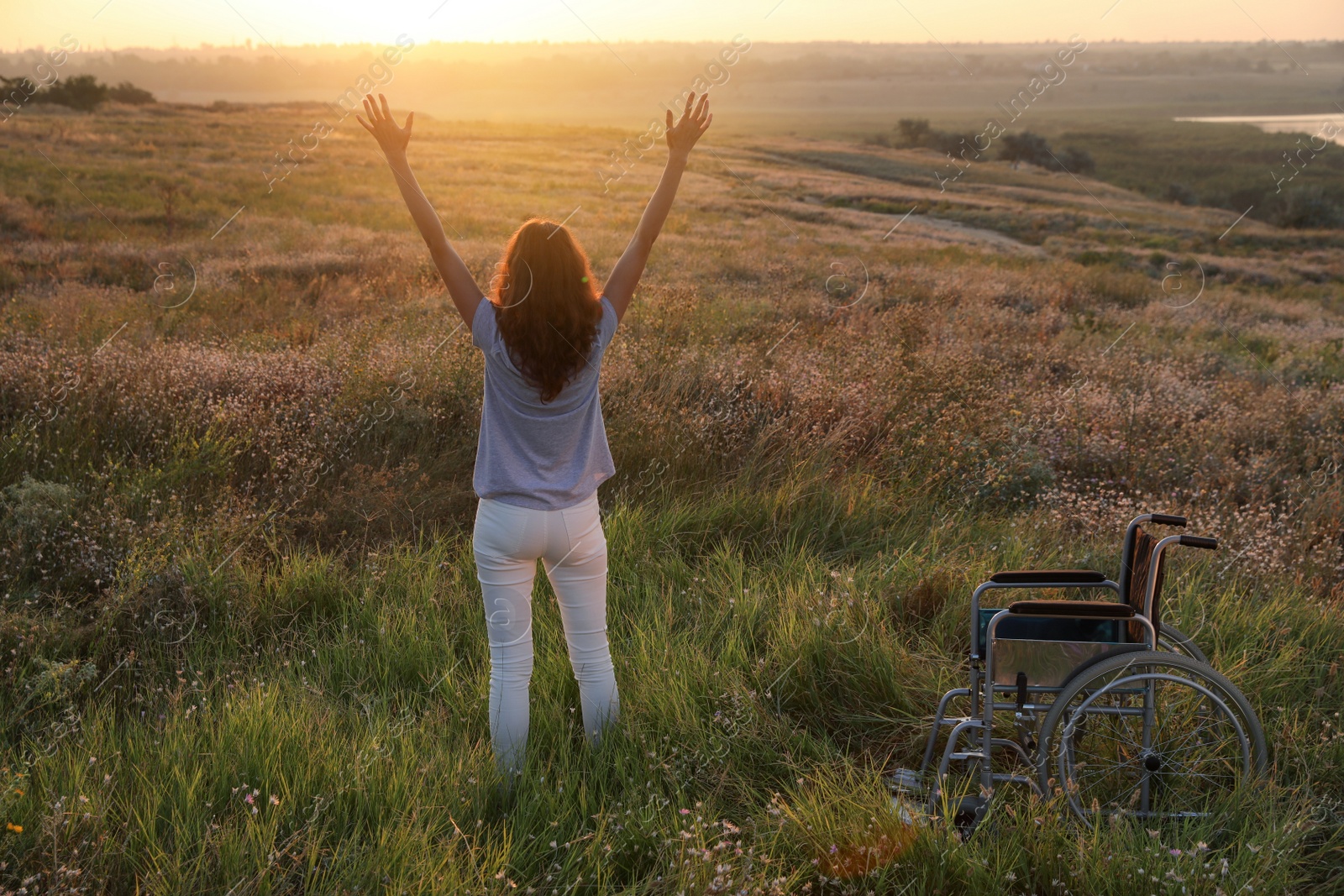 Photo of Woman standing near wheelchair in evening outdoors, back view. Healing miracle