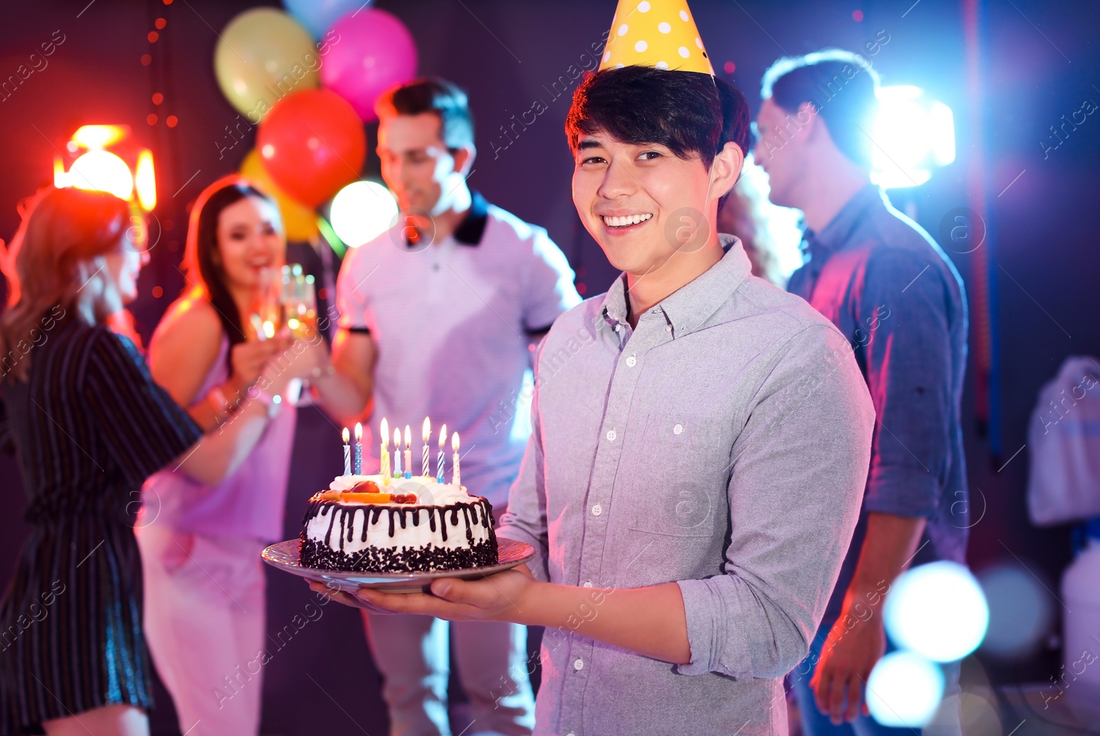 Photo of Young man with birthday cake at party in nightclub