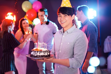 Photo of Young man with birthday cake at party in nightclub