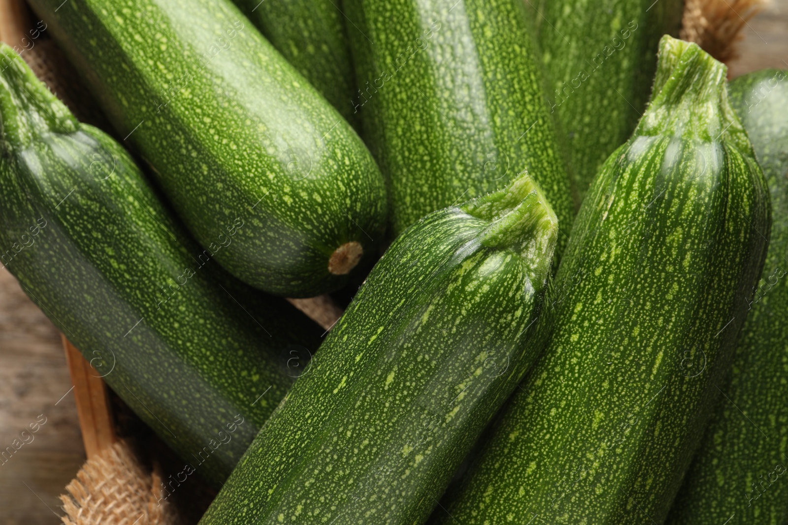 Photo of Raw ripe zucchinis in wooden crate, closeup