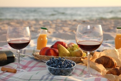 Blanket with wine, juice and snacks for picnic on sandy beach