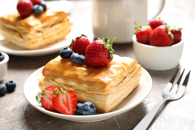 Photo of Fresh delicious puff pastry with sweet berries on grey marble table, closeup