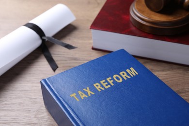 Book with text TAX REFORM on wooden table, closeup view