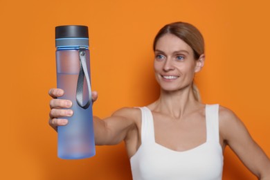 Photo of Sportswoman with bottle of water on orange background