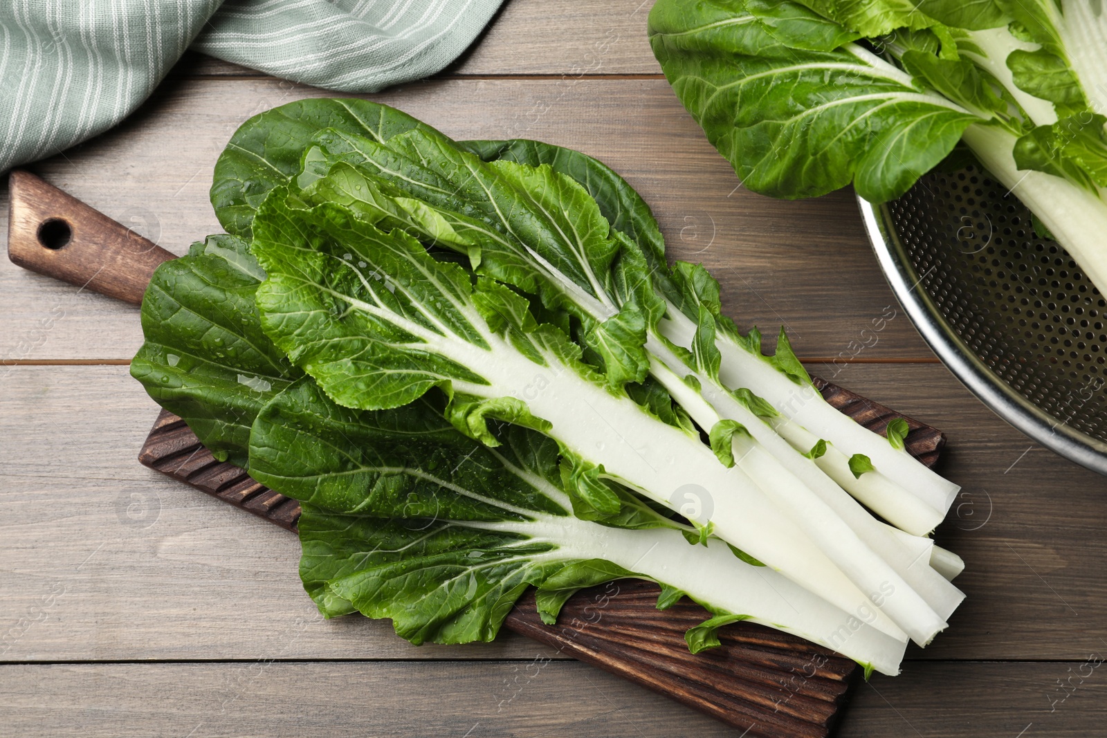 Photo of Fresh green pak choy cabbage with water drops on wooden table, flat lay