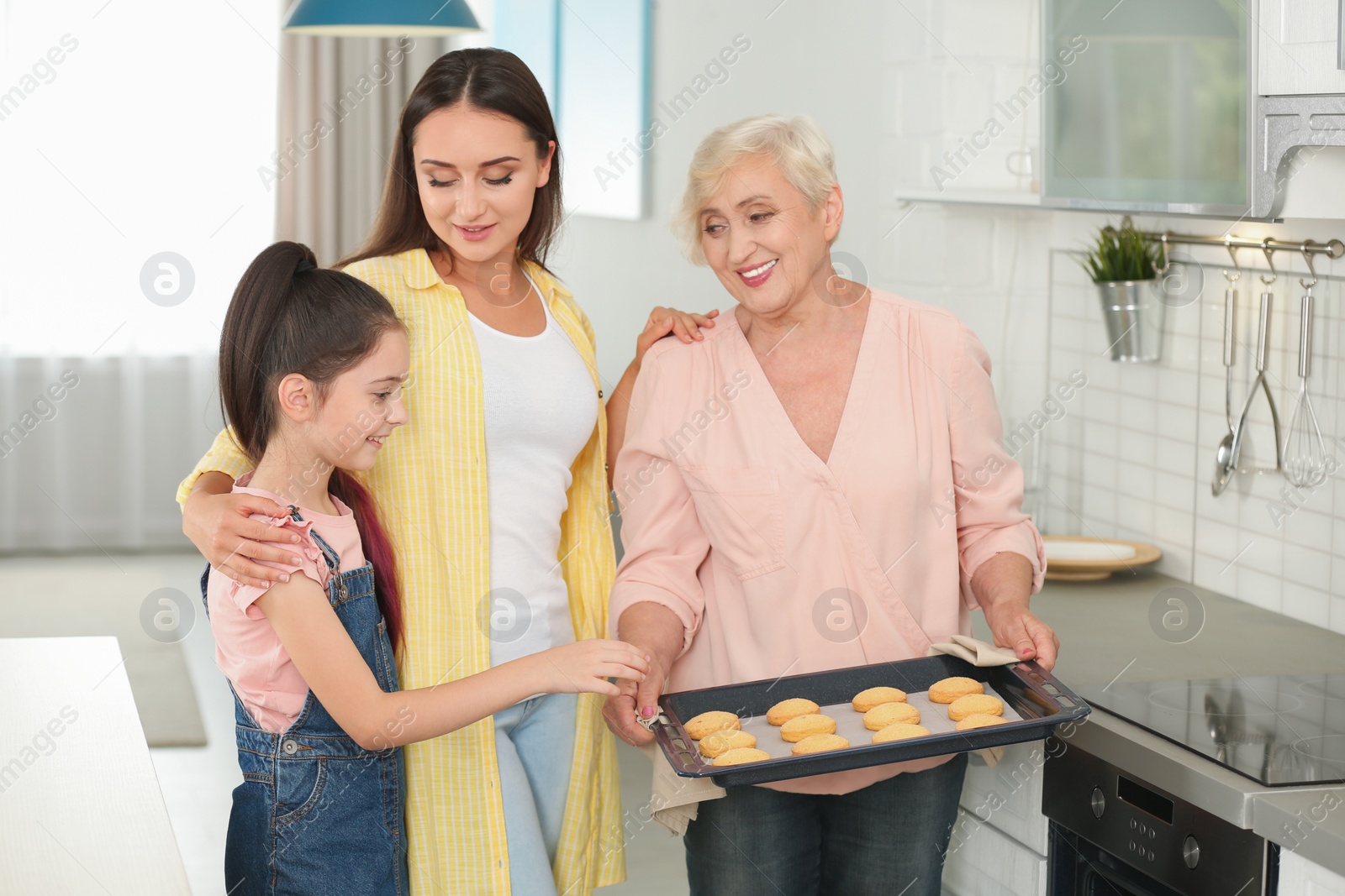 Photo of Happy grandmother helping her family to bake cookies in kitchen