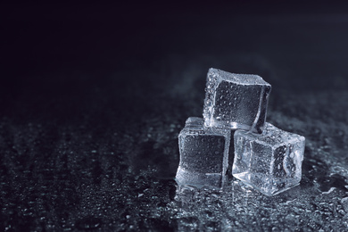 Photo of Crystal clear ice cubes with water drops on black background. Space for text
