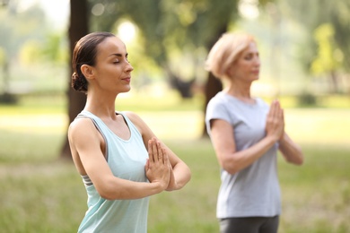 Women practicing yoga in park at morning