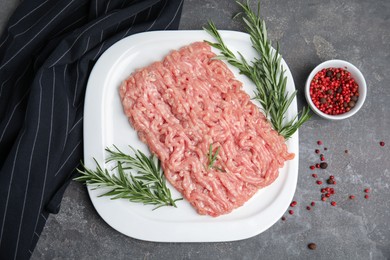 Photo of Raw chicken minced meat with rosemary and spices on grey table, flat lay