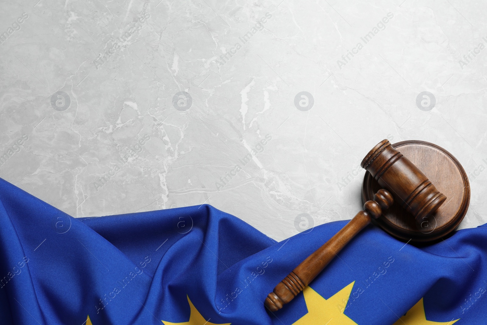 Photo of Judge's gavel and flag of European Union on light grey marble table, flat lay. Space for text