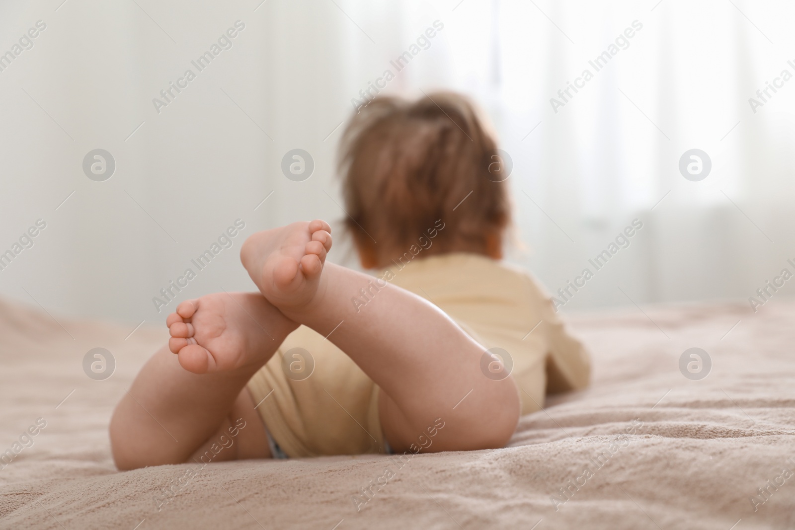 Photo of Little baby lying on bed indoors, focus on legs