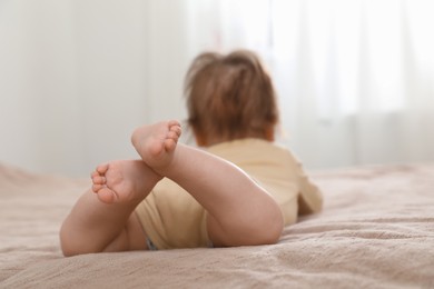 Photo of Little baby lying on bed indoors, focus on legs