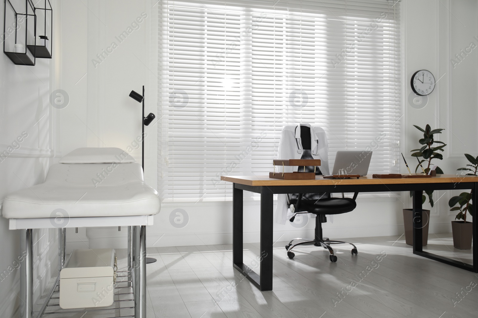 Photo of Modern medical office interior with doctor's workplace and examination table