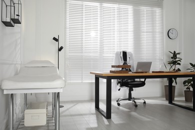 Modern medical office interior with doctor's workplace and examination table