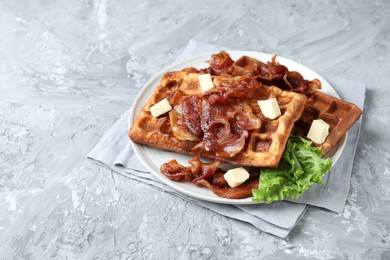 Delicious Belgium waffles served with fried bacon and butter on grey table, space for text