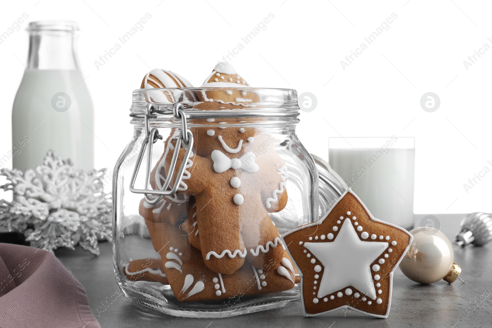 Photo of Tasty Christmas cookies and milk on grey table against white background, closeup
