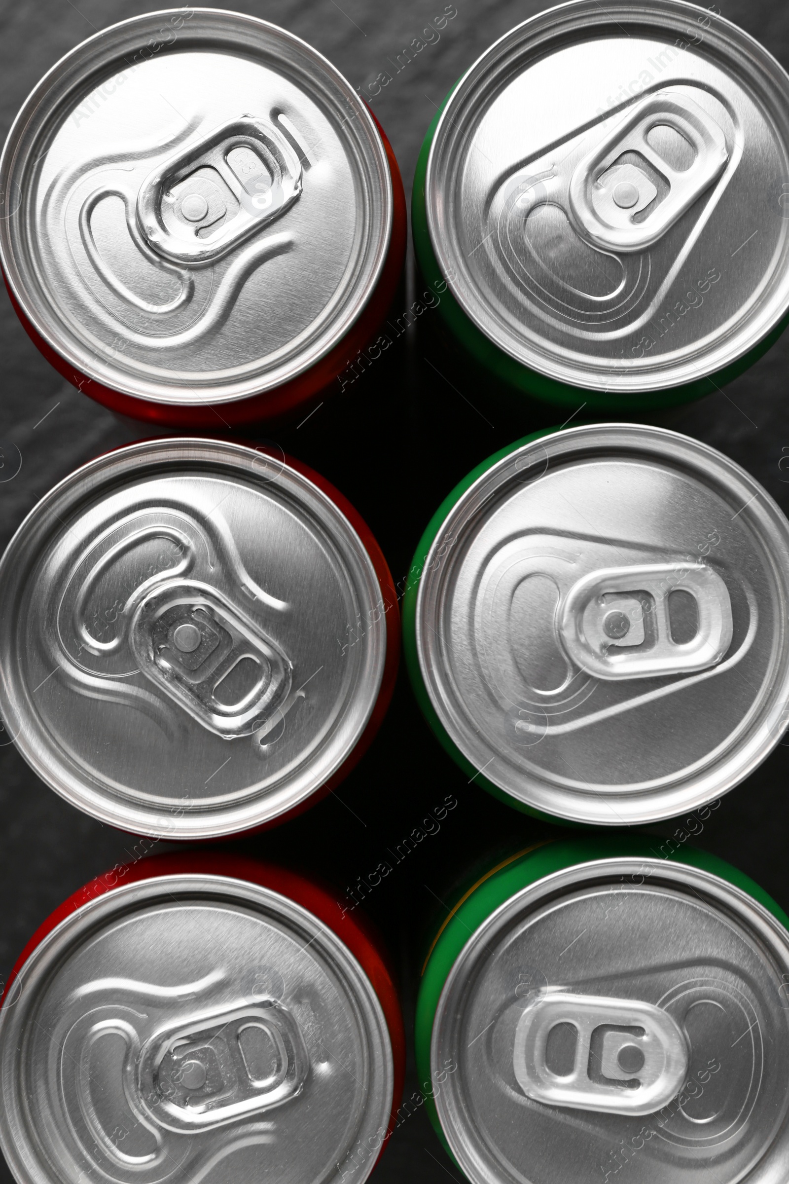 Photo of Energy drink in cans on black background, top view. Functional beverage