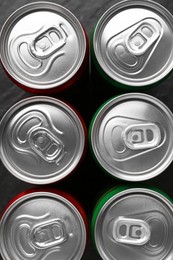 Photo of Energy drink in cans on black background, top view. Functional beverage