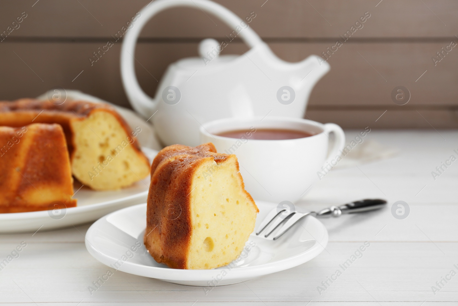 Photo of Piece of delicious homemade yogurt cake served on white wooden table