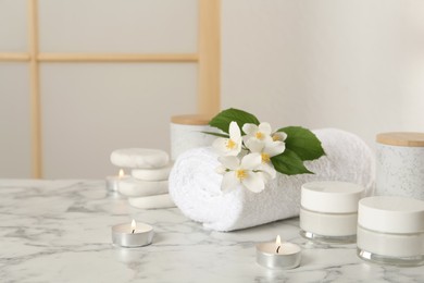 Photo of Composition with beautiful jasmine flowers and skin care products on white marble table indoors, space for text