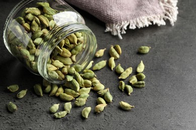 Jar with dry cardamom pods on dark grey table