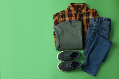 Photo of Stylish child clothes and shoes on green background, flat lay. Space for text