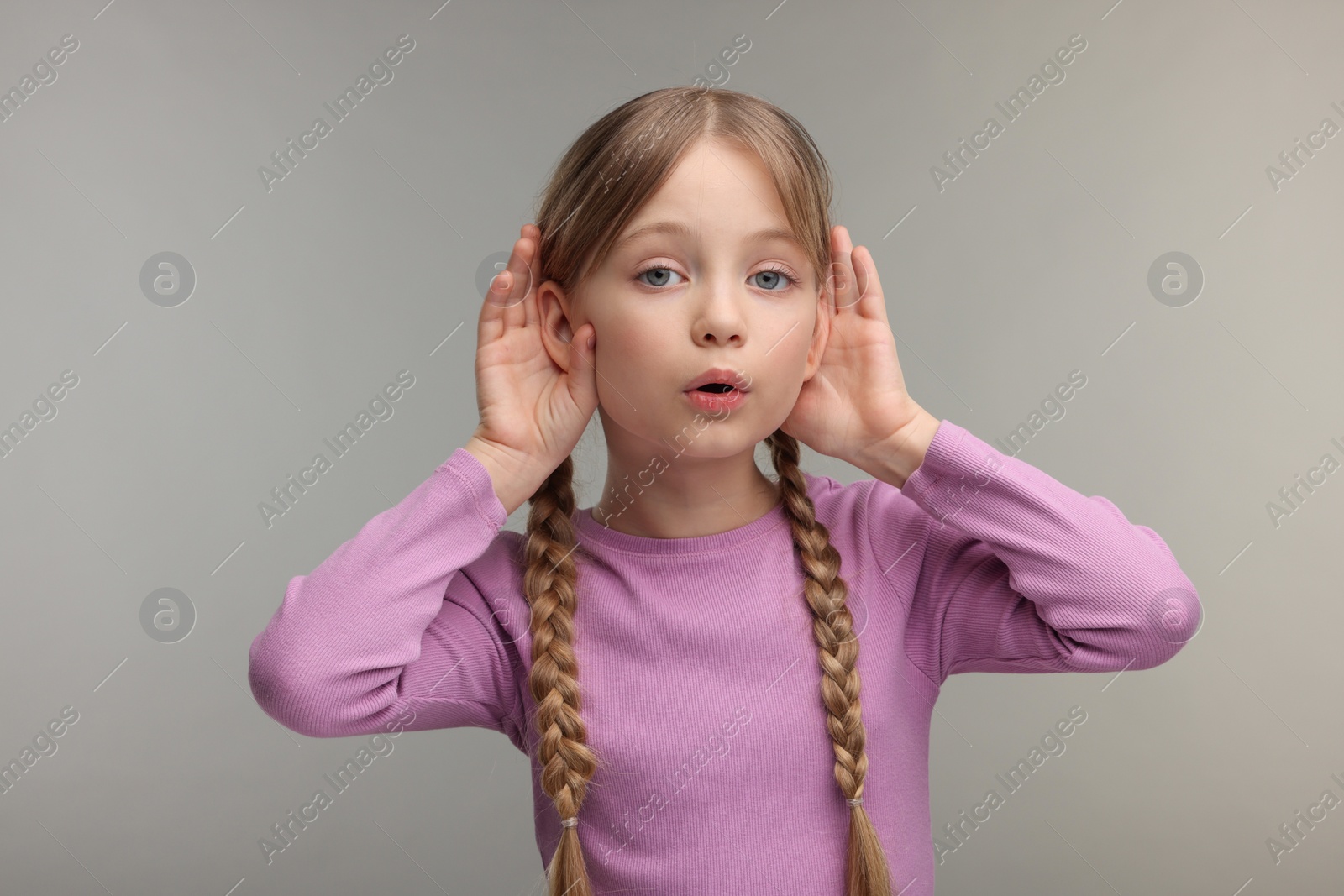 Photo of Little girl with hearing problem on grey background