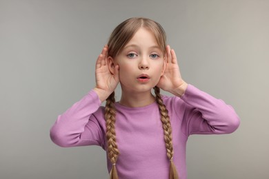 Little girl with hearing problem on grey background