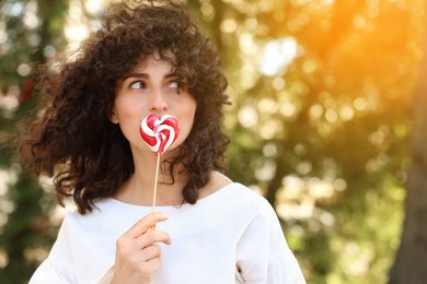 Photo of Beautiful woman with lollipop outdoors, space for text