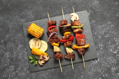 Photo of Delicious shish kebabs with grilled vegetables on grey textured table, top view