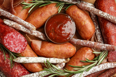 Different types of sausages served on wooden board, top view