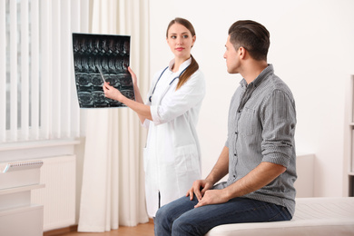 Photo of Orthopedist showing X-ray picture to patient in clinic