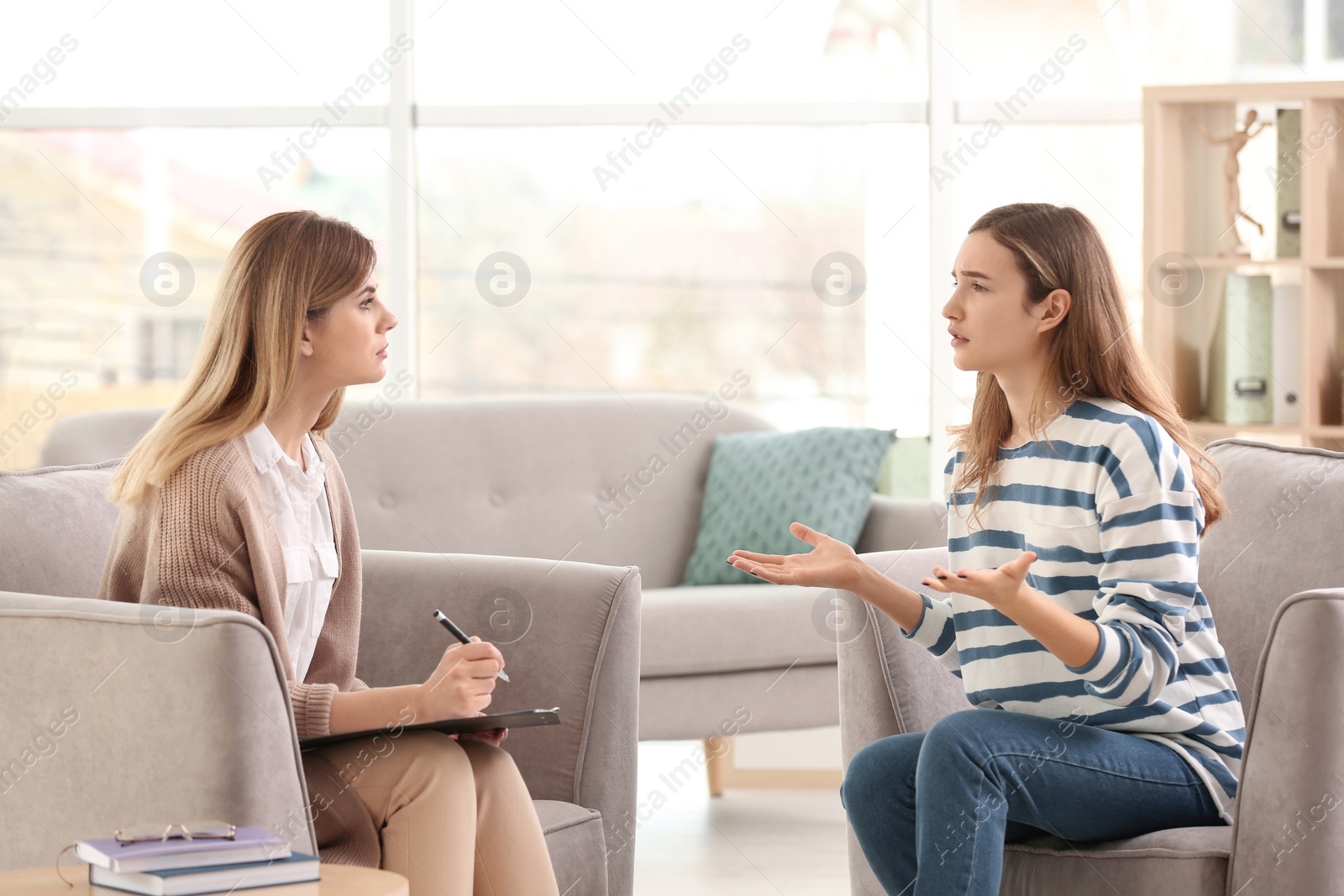 Photo of Young female psychologist working with teenage girl in office