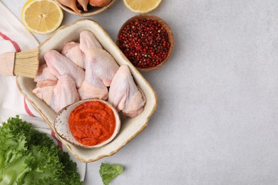 Photo of Flat lay composition with marinade, raw chicken and other products on light textured table. Space for text