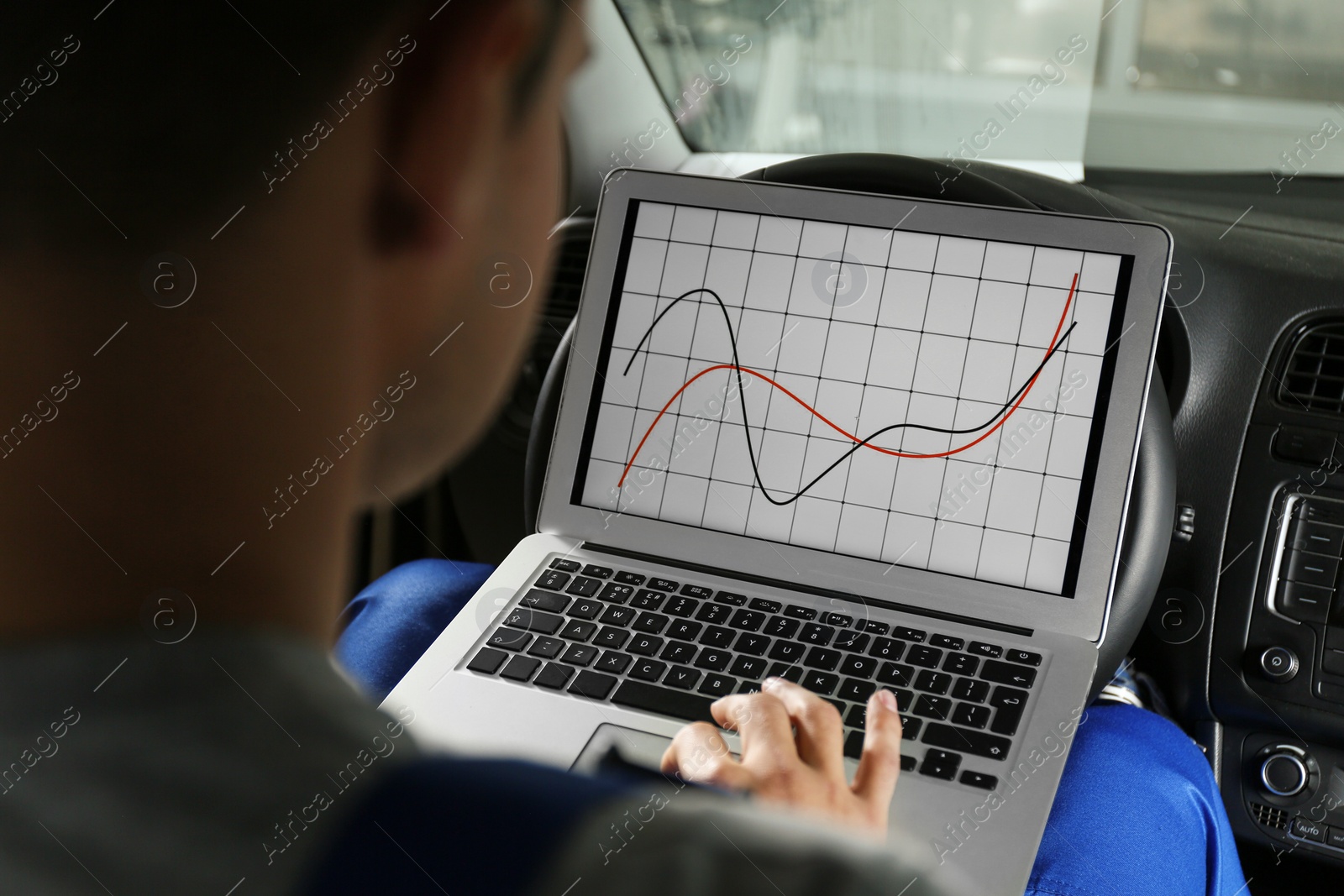 Photo of Mechanic with laptop doing car diagnostic at automobile repair shop, closeup