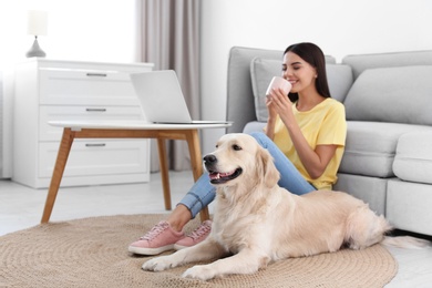 Photo of Young woman and her Golden Retriever dog in living room