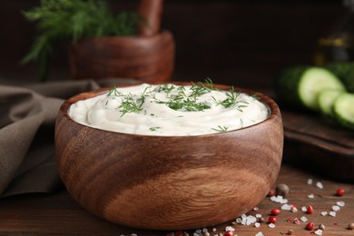 Tasty creamy dill sauce in bowl on wooden table, closeup