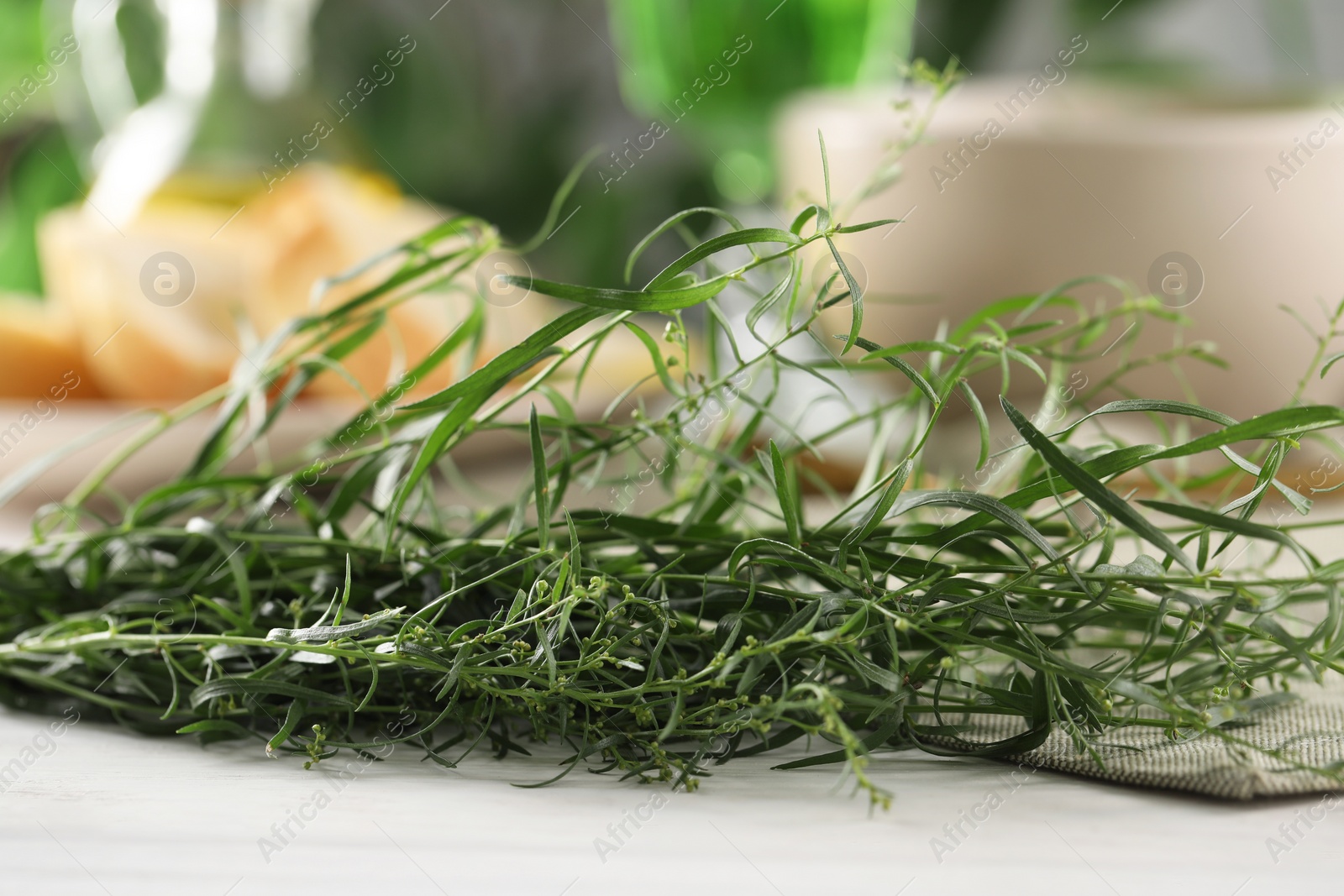 Photo of Fresh tarragon sprigs on white table, closeup