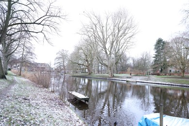 Picturesque view of water canal, trees and buildings on winter day