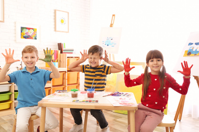 Photo of Cute little children with painted palms in room