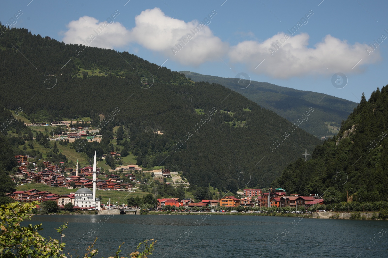 Photo of Buildings under mountains near lake on sunny day