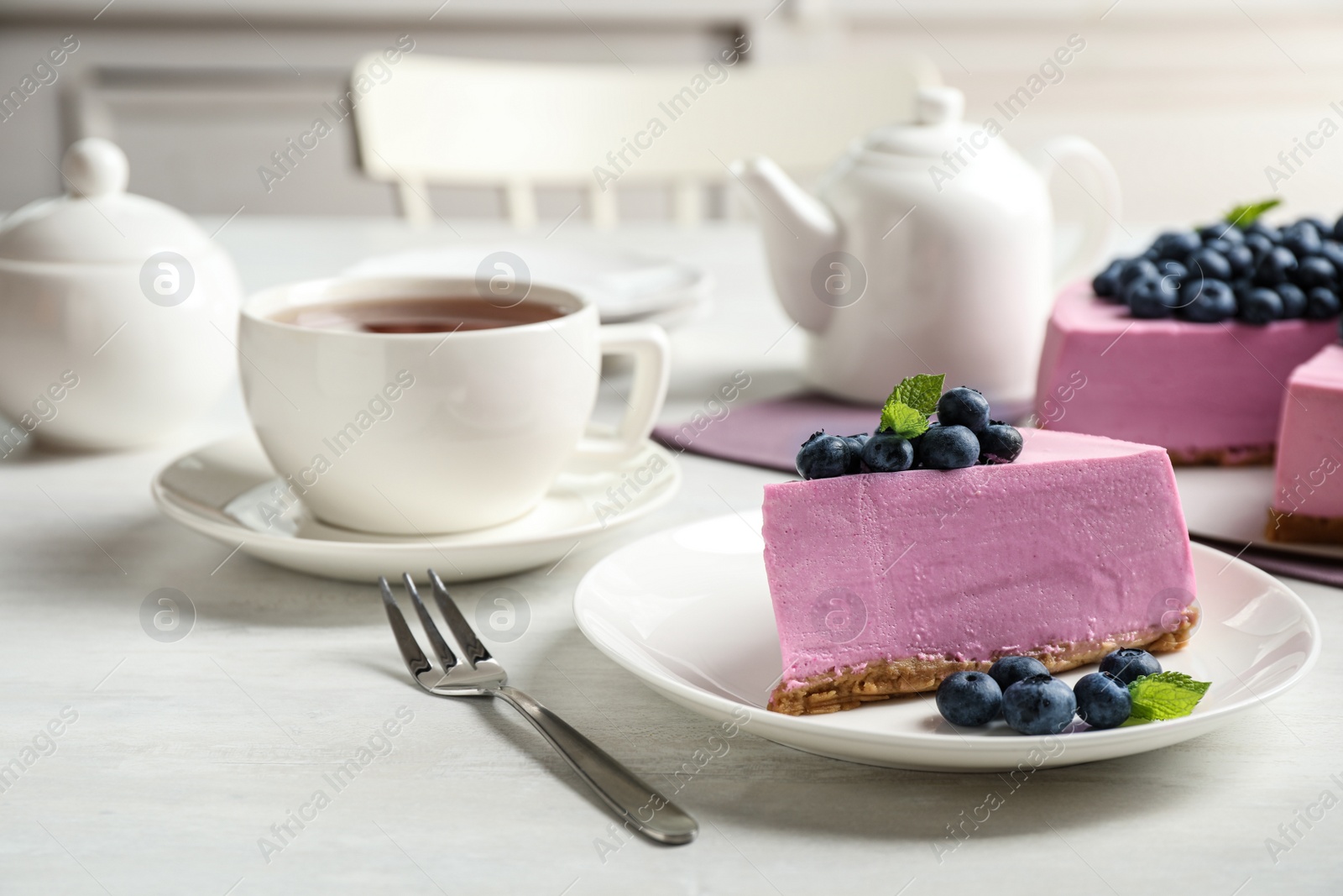 Photo of Plate with piece of tasty blueberry cake served on light table. Space for text