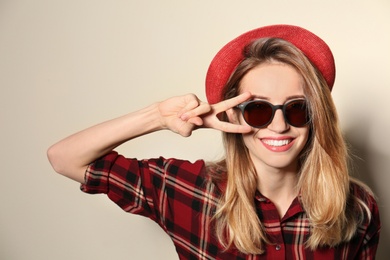 Photo of Young woman wearing stylish sunglasses on beige background